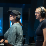 Two women ready to shoot at the range wearing proper attire and ear protection.